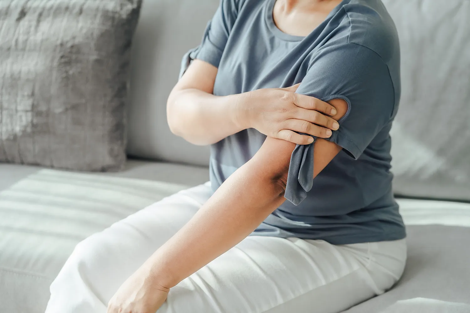 woman sit in couch having shoulder pain